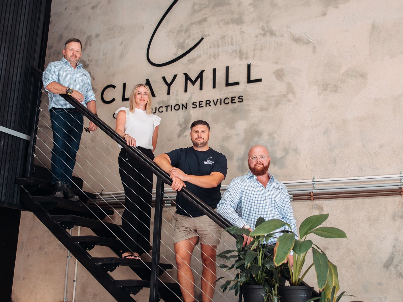 The Claymill team on the office staircase under the Claymill sign